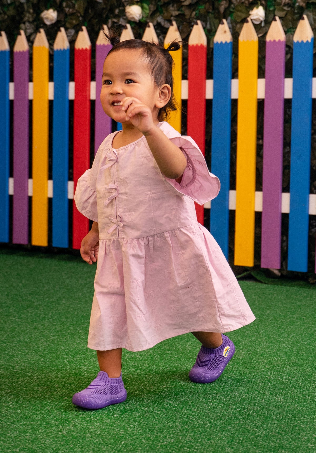 Child in a pink dress wearing shoes 
